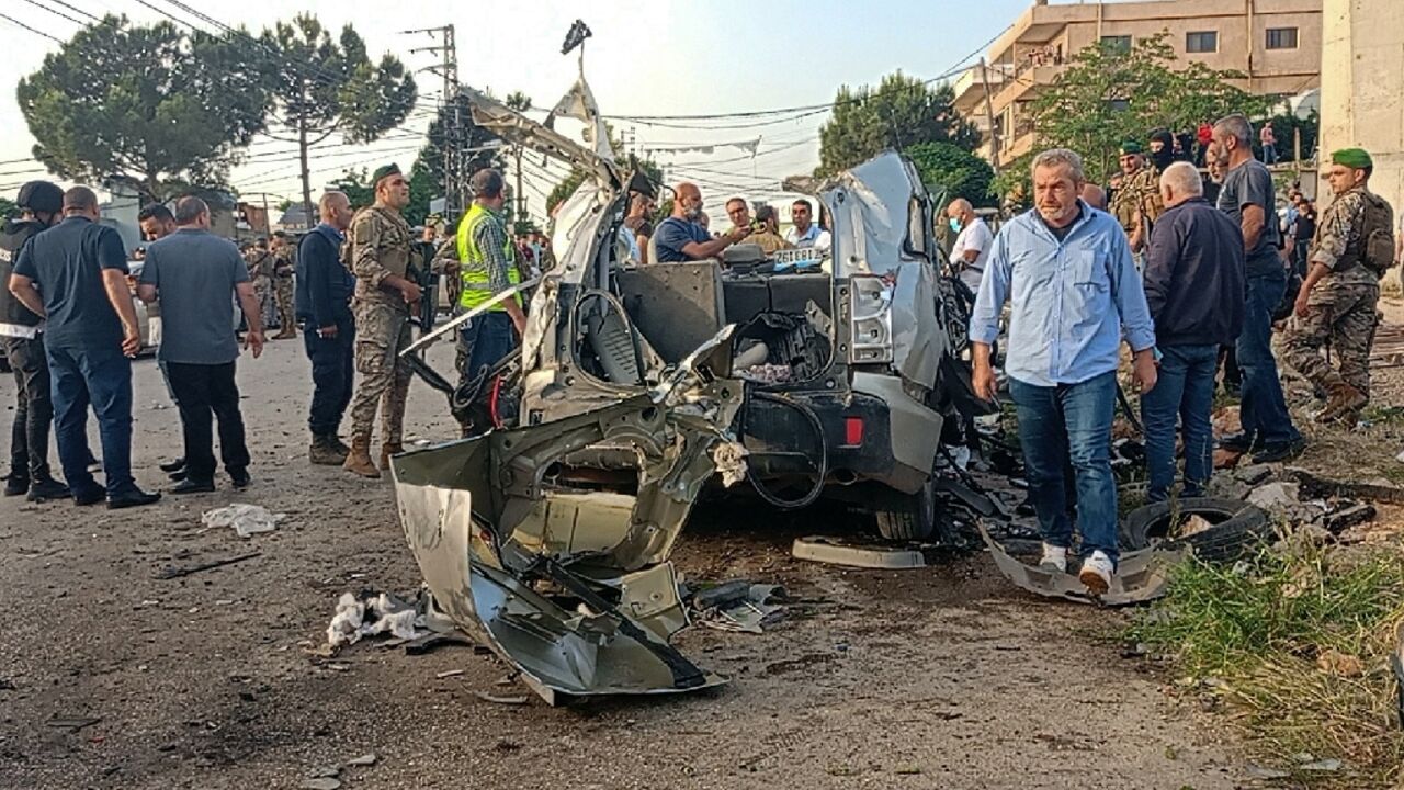 Lebanese soldiers and onlookers gather around the remnants of a car after it was hit by an Israeli strike, reportedly killing a Hamas commander, in Lebanon's Bekaa Valley