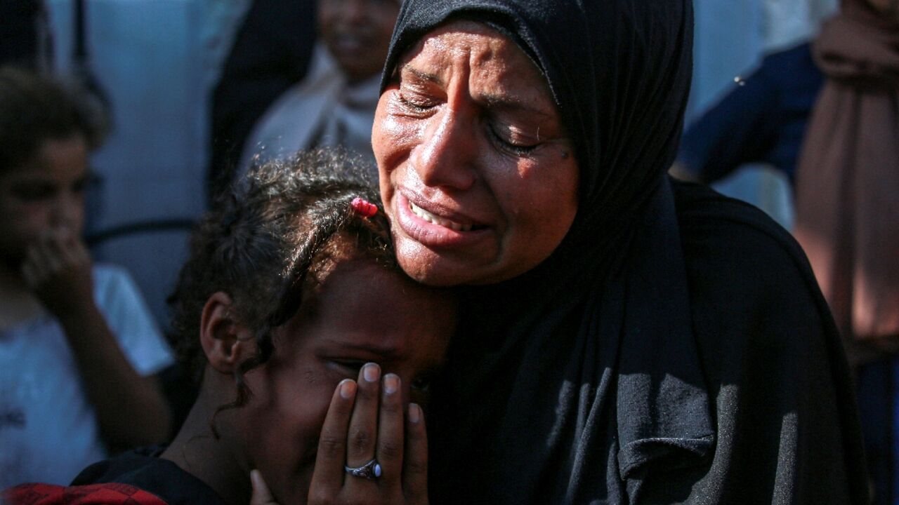 A Palestinian woman and a child cry as they mourn the death of a loved one outside a hospital in central Gaza