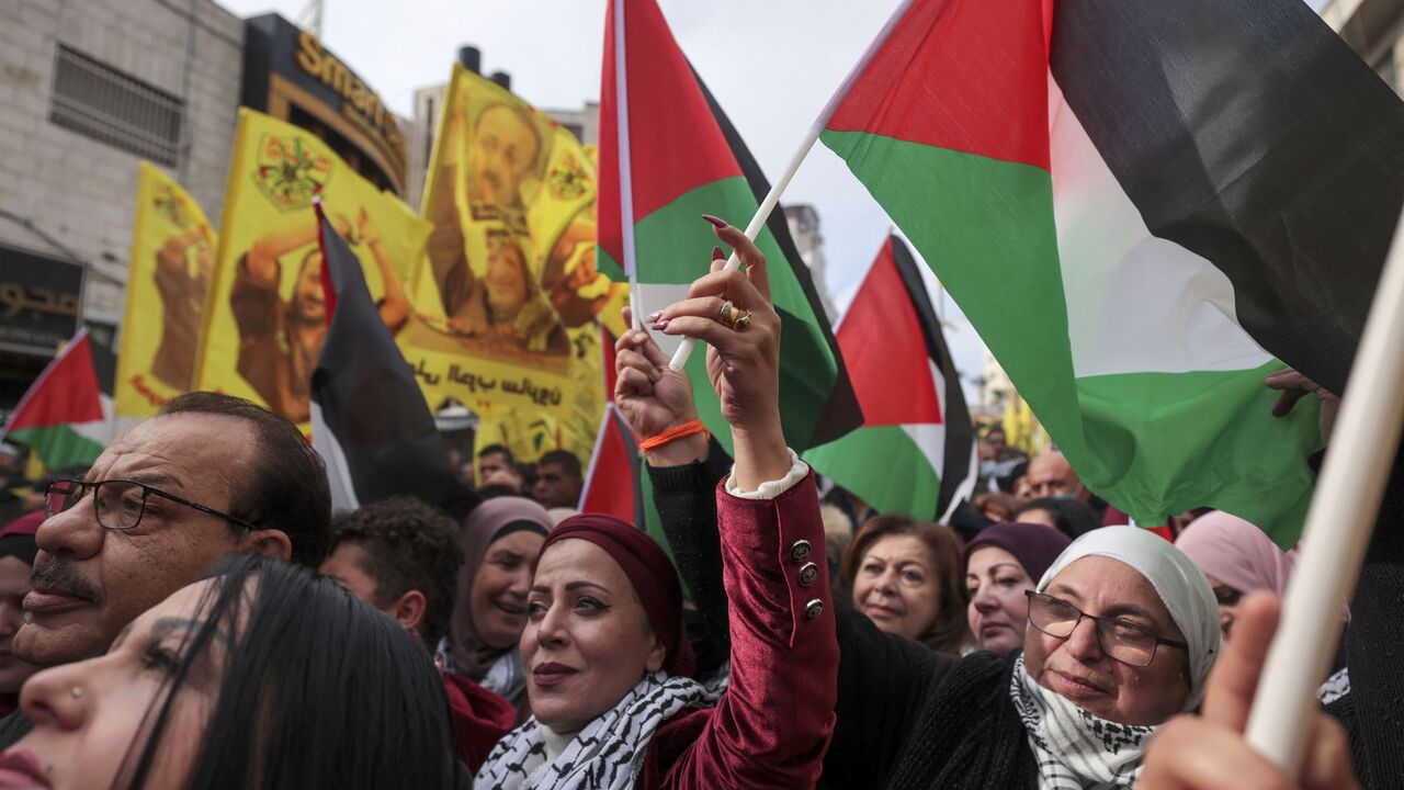 Palestinians wave their national flags, and banners bearing the image of jailed Fatah leader Marwan Barghuti with a slogan demanding his release and referring to him as the "symbol of freedom", during a celebration marking the 57th anniversary of Fatah movement's foundation, in Ramallah, in the Israeli-occupied West Bank, on December 30, 2021.