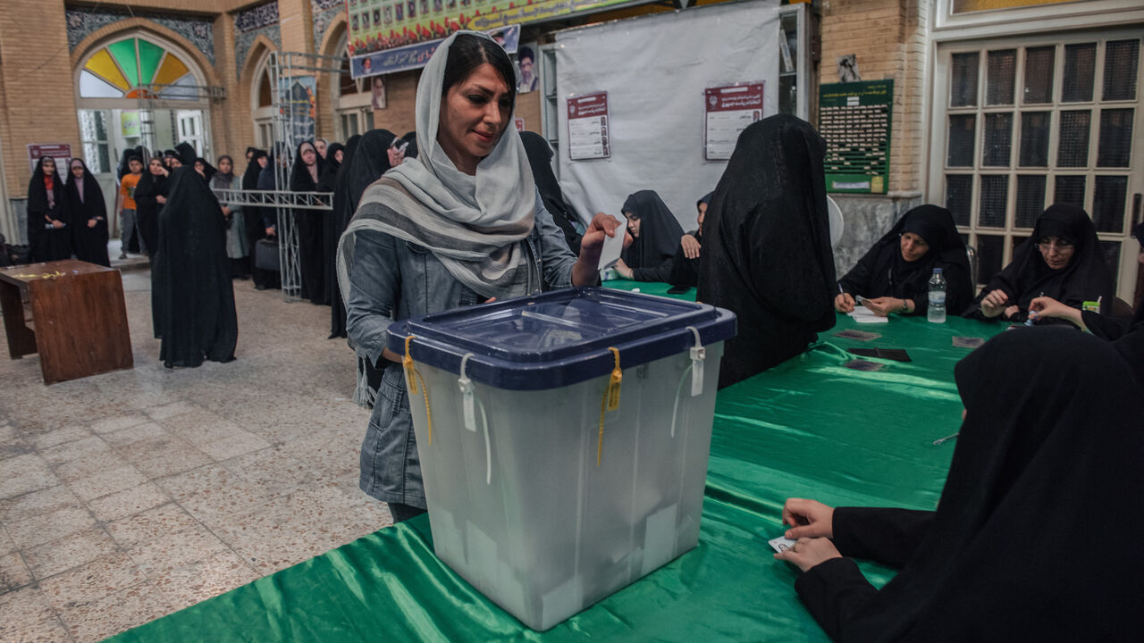 An Iranian woman casts her vote at a polling station in Tehran during Iran's presidential election on June 28, 2024. 