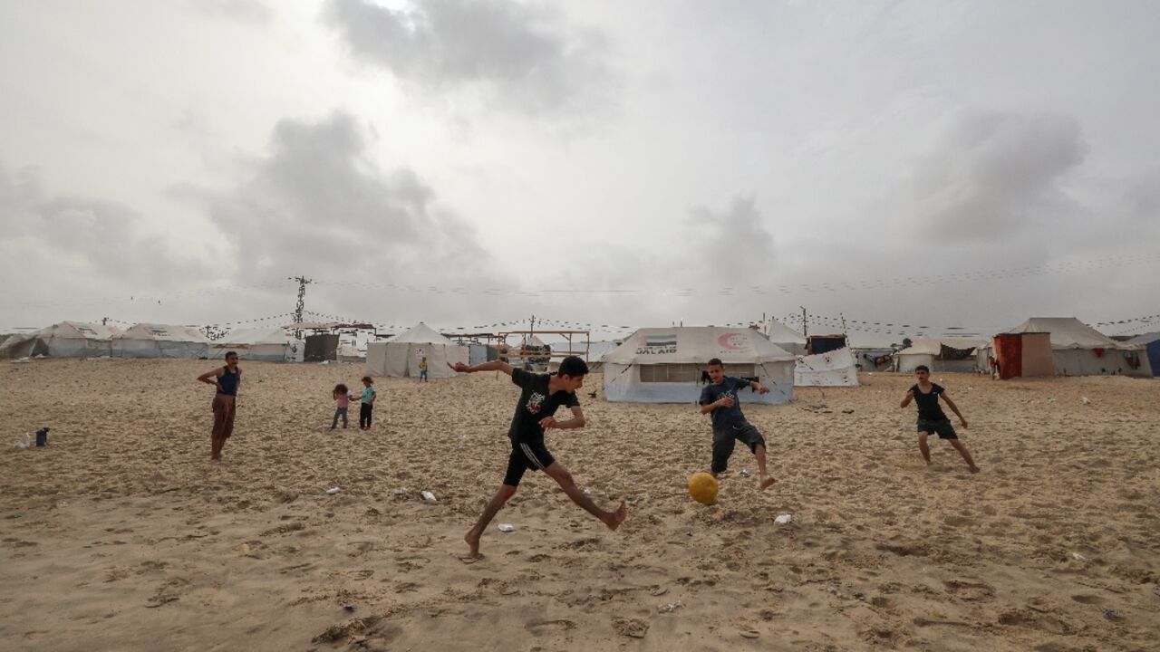 Displaced Palestinian youths play football on the beach outside their camp tents in Rafah in the southern Gaza Strip on April 26, 2024 amid the ongoing conflict between Israel and the Palestinian militant group Hamas
