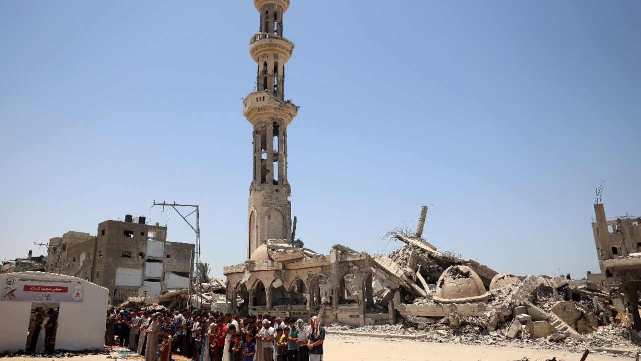 Muslims perform the Friday noon prayer in front of a destroyed mosque in Khan Yunis in the southern Gaza Strip, ahead of Eid al-Adha