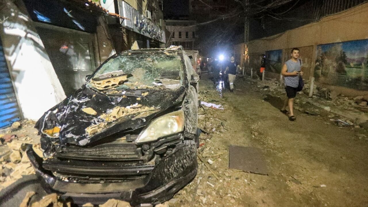 A destroyed car Tuesday outside a Beirut building destroyed by an Israeli military strike
