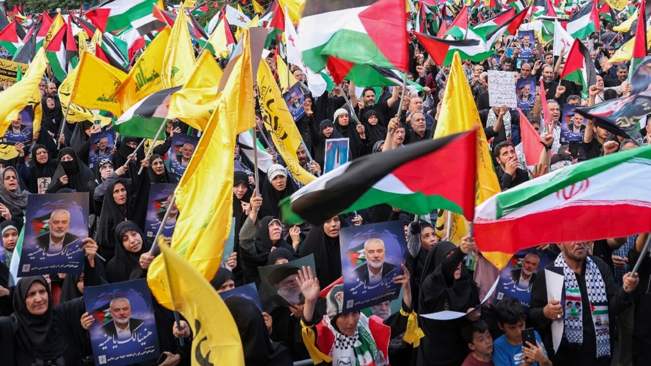 Iranians wave Palestinian flags and hold portraits of slain Hamas leader Ismail Haniyeh at a protest denouncing his killing