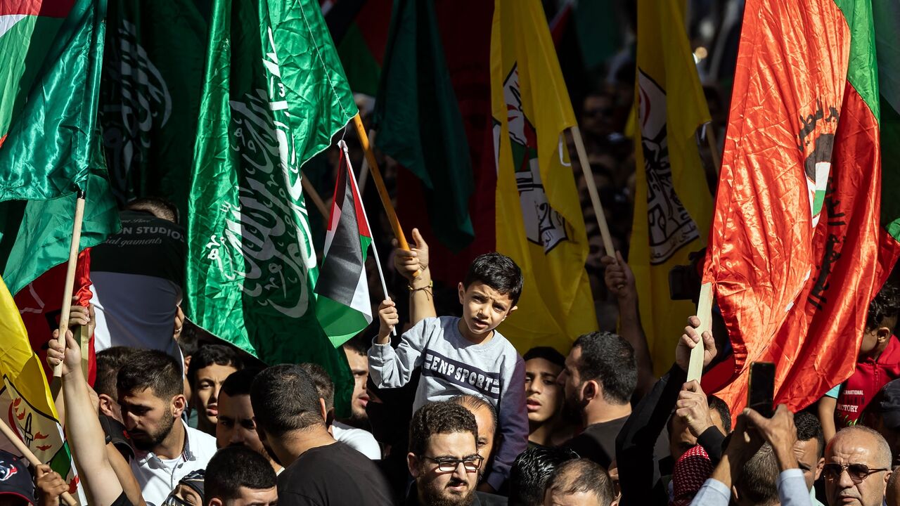 Palestinians lift flags of the Hamas and Fatah groups as they demonstrate in Ramallah in the occupied West Bank on November 10, 2023, amid ongoing battles between Israel and the Hamas movement in the Gaza Strip. 