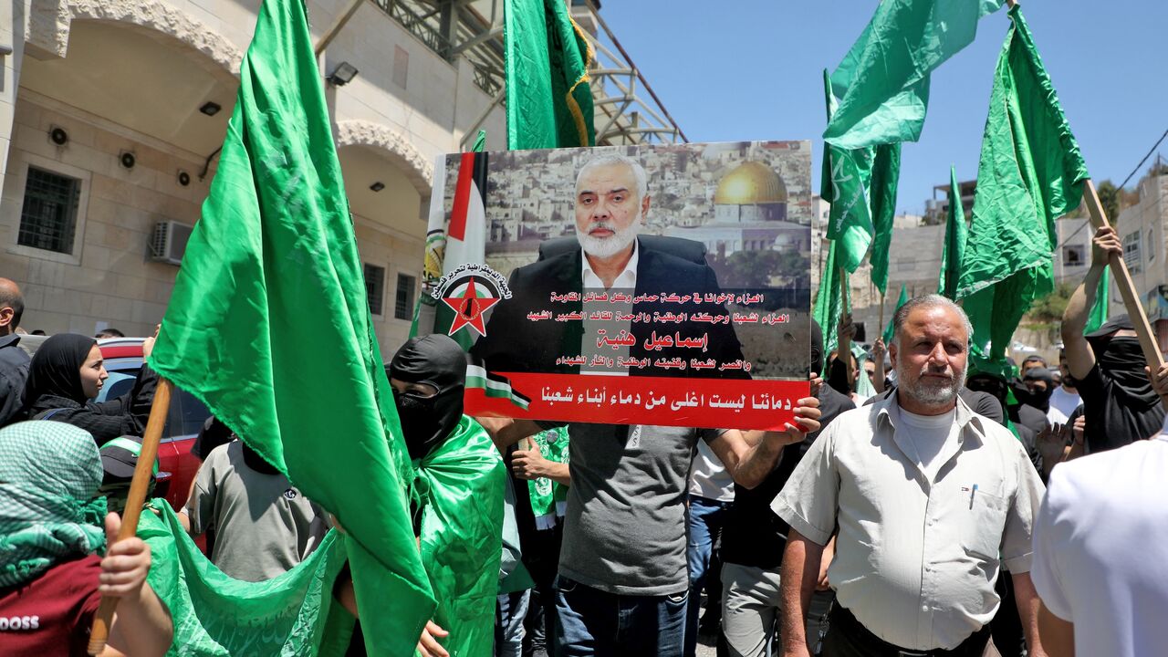 Palestinians carry a placard bearing the image of the leader of the militant Hamas group during a protest in the occupied West Bank city of Hebron on July 31, 2024, denouncing his killing.