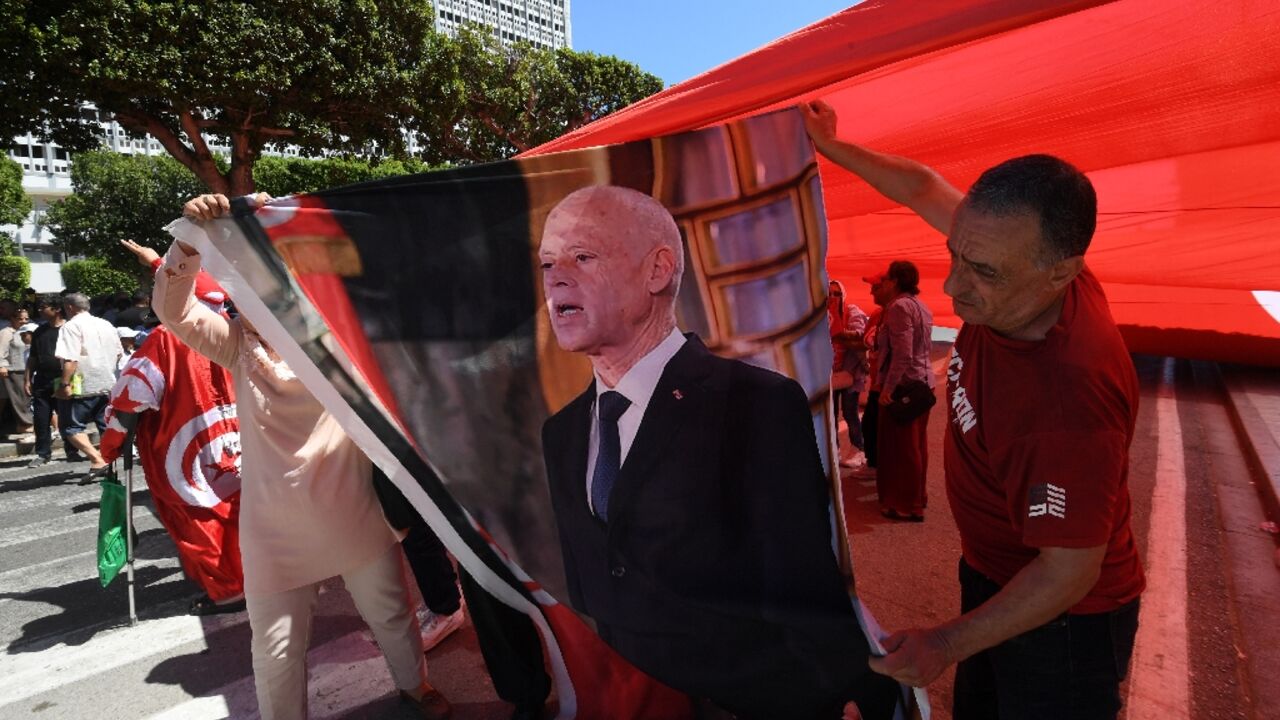 Supporters of Tunisian President Kais Saied hold his image during a rally along the Habib Bourguiba Avenue in Tunis, on July 25