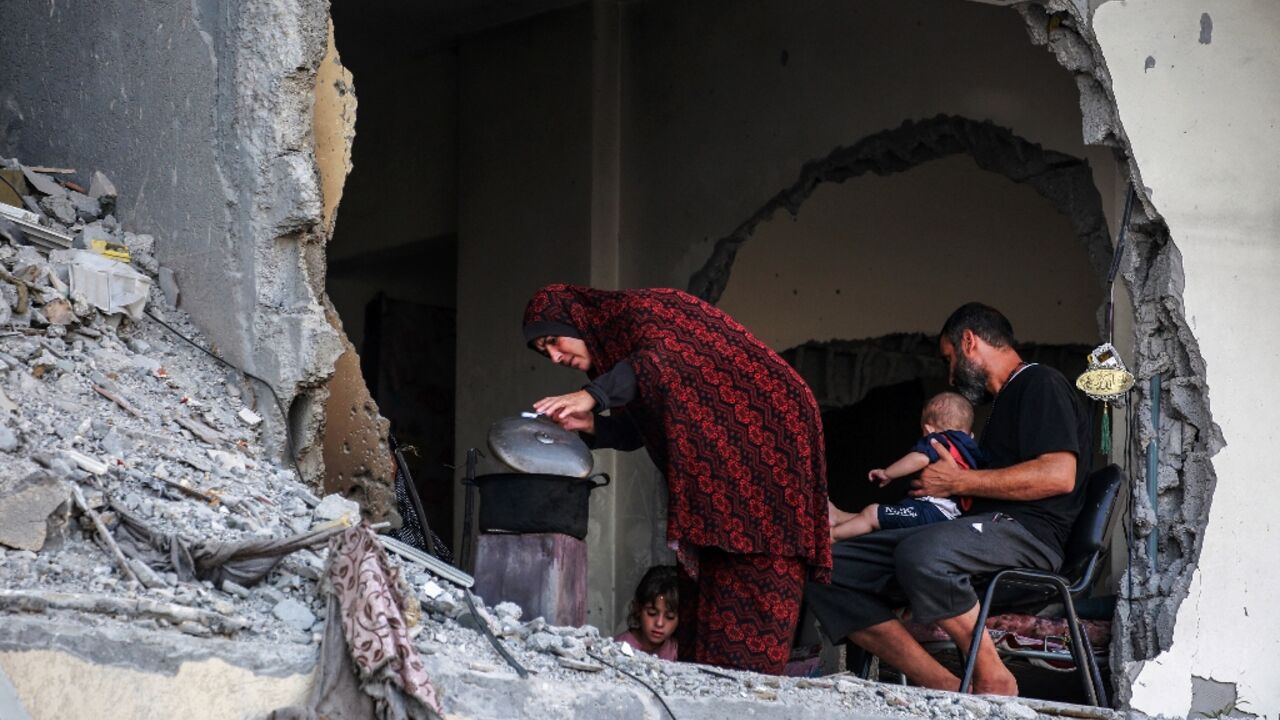 A Palestinian family gathers around a makeshift wood stove in a damaged building in Khan Yunis, southern Gaza