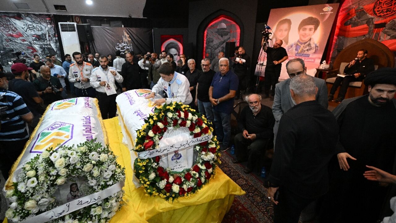 People gather around the coffins of two children, Hassan and Amira Muhammed Fadallah, during their funeral the day after they were killed in an Israeli strike on a building in Beirut's southern suburbs