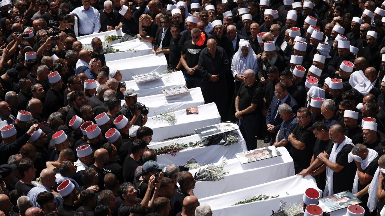 Druze elders and mourners surround the coffins of many of the 12 people killed in a rocket strike from Lebanon in the Israeli-annexed Golan Heights
