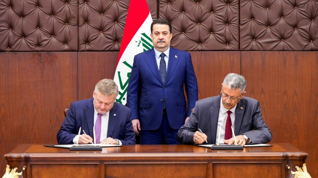 A picture released by the media office of Iraqi Prime Minister Mohamed Shia al-Sudani shows him  looking on as BP CEO, Murray Auchincloss (L) and Iraqi Oil Minister Hayan Abdul Ghani al-Sawad sign a memorandum of understanding to develop oil and gas fields in Kirkuk.