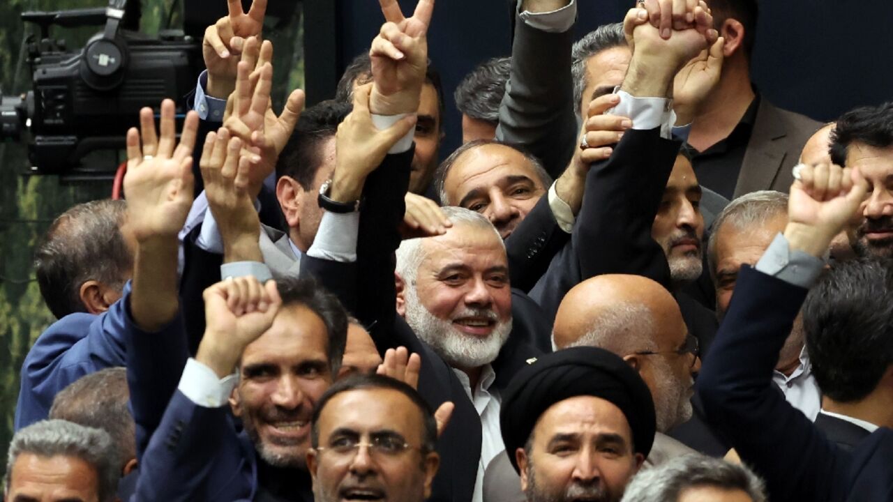 A day before his killing, Ismail Haniyeh, political chief of Palestinian militant group Hamas (C), flashes the victory sign among other officials during the swearing-in ceremony for Iran's new president