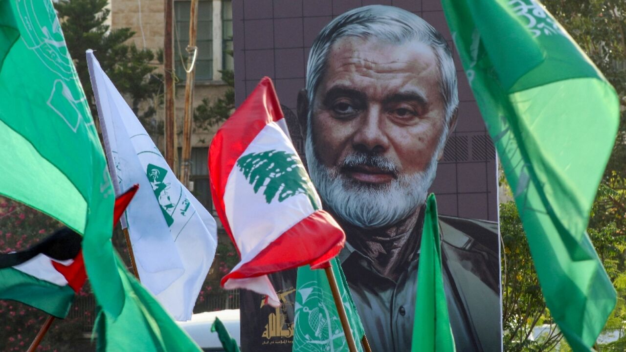 A portrait of slain Hamas political leader Ismail Haniyeh provides a backdrop to a demonstration, in Lebanon's Sidon city, denouncing his killing and that of a senior Hezbollah's commander
