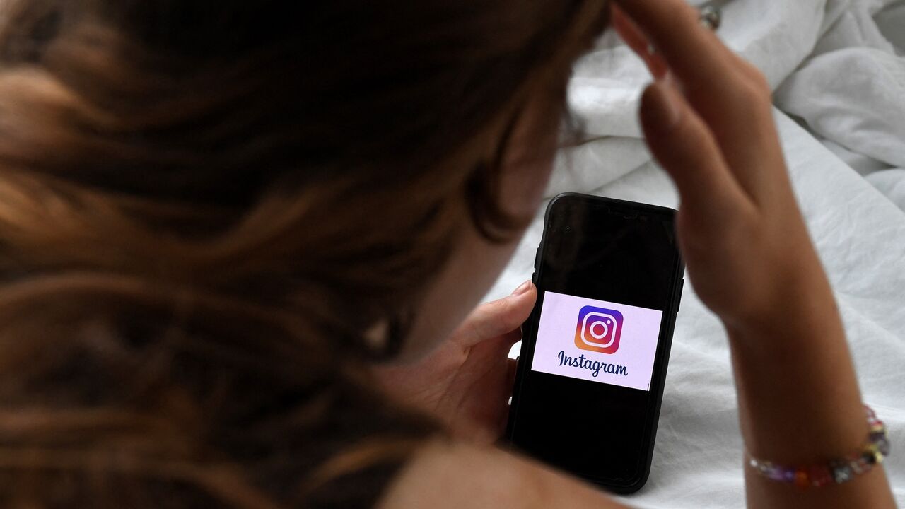 Photo illustration of a person looking at a smartphone displaying an Instagram logo in Arlington, Virginia, Aug. 17, 2021.