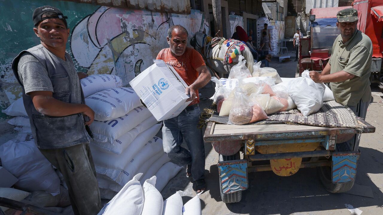 Palestinians carry bags of flour provided as aid to poor families at the United Nations Relief and Works Agency for Palestine Refugees (UNRWA) distribution center, in the Al-Shati refugee camp in Gaza city on June 5, 2023.