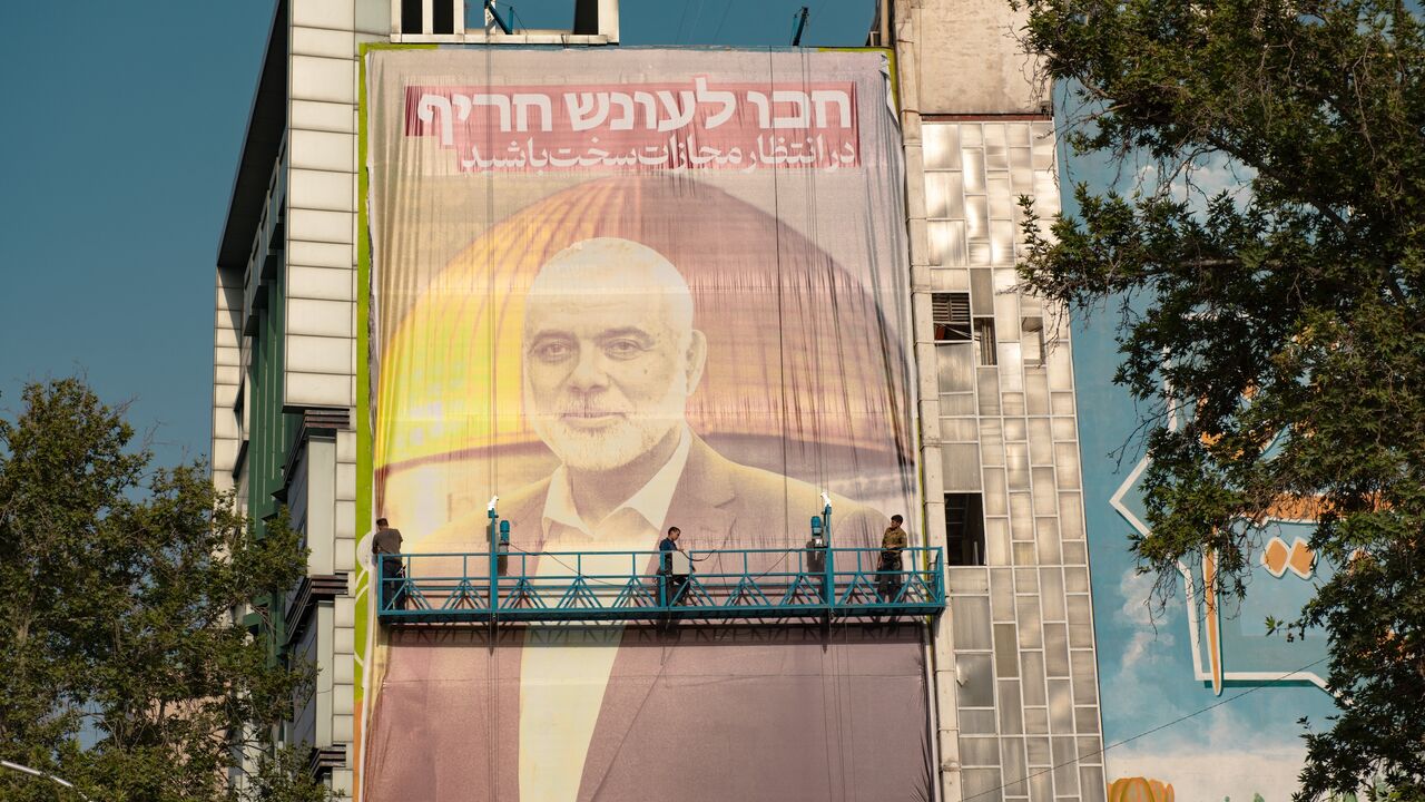 Workers hang a billboard in Palestine Square bearing a portrait of slain Hamas leader Ismail Haniyeh with slogan "Expect severe punishment" in Persian and Hebrew, Tehran, July 31, 2024.