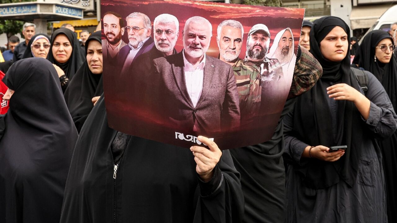 An Iranian woman holds a poster displaying slain militant leaders including Hamas's Ismail Haniyeh during his funeral procession in Tehran