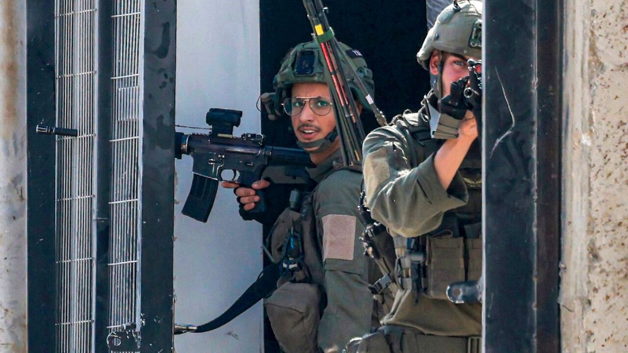 Israeli soldiers take position in a doorway during a two-day military operation in the West Bank city of Tulkarem