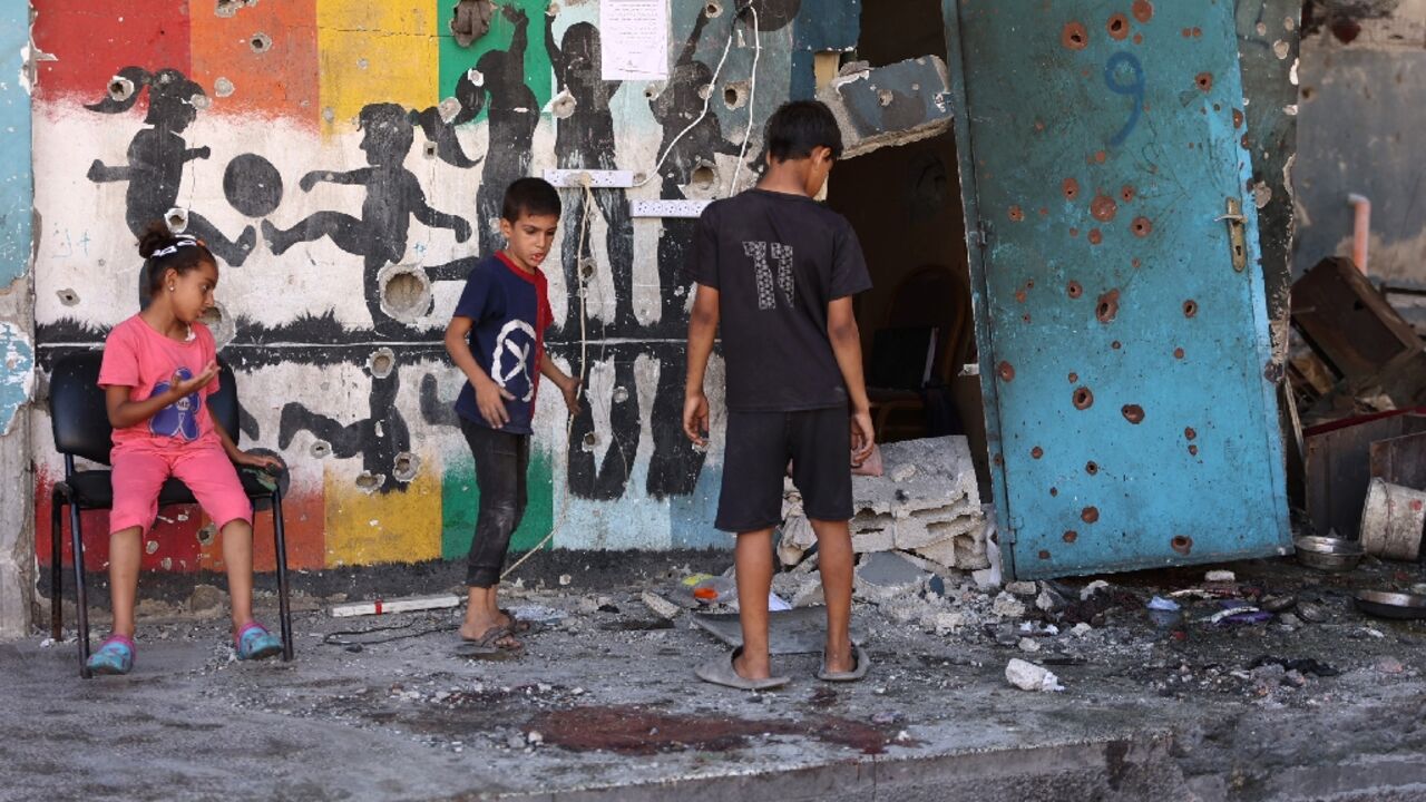 Children inspect the damage at the site of the Israeli strike on a school housing displaced Palestinians