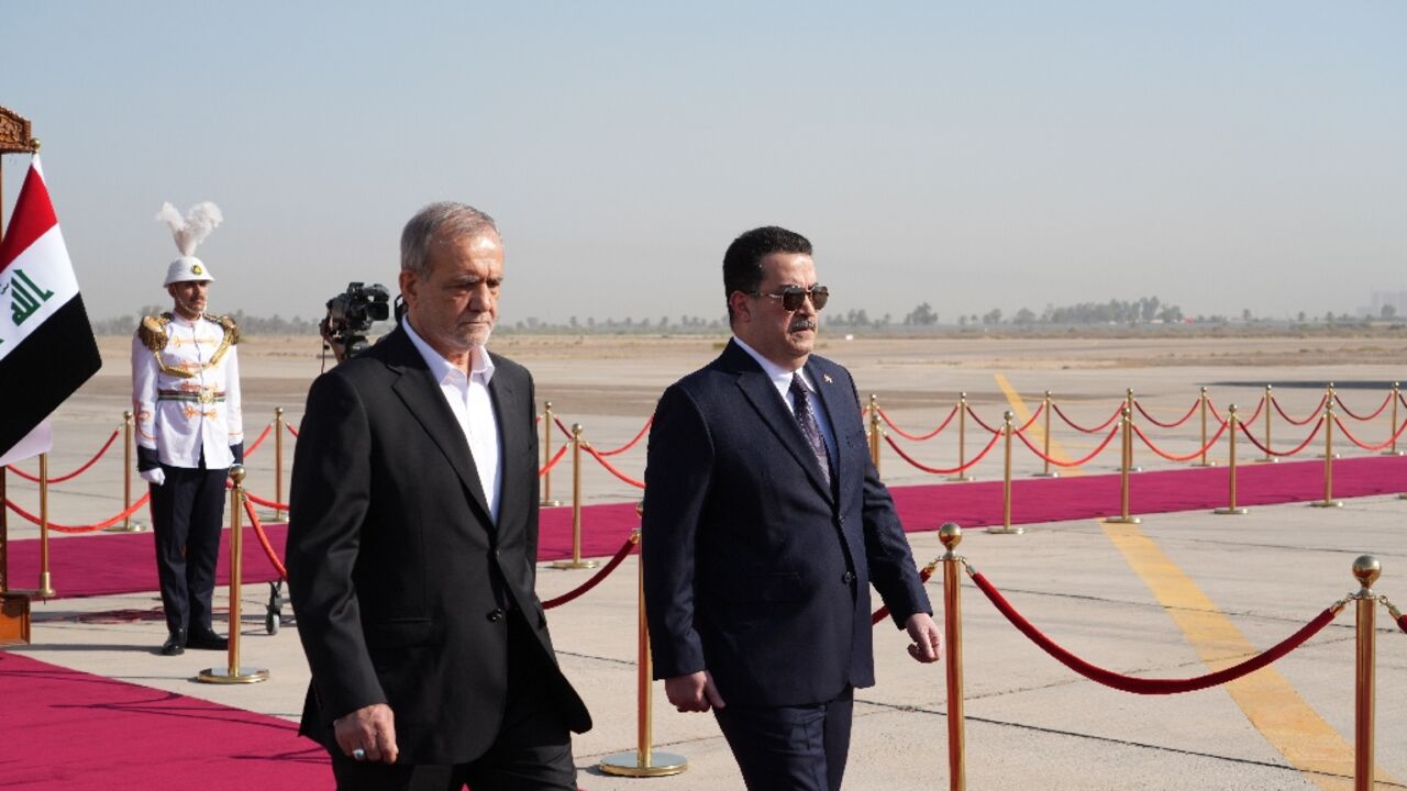 Iraqi Prime Minister Mohamed Shia al-Sudani (R) welcomes Iran's new president, Masoud Pezeshkian, to Baghdad on his first foreing visit since taking office in July