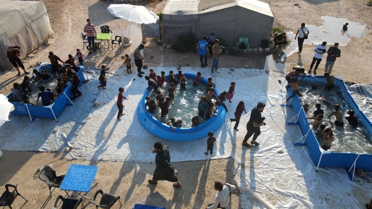 Displaced Syrian children play in swimming pools set up by the Smile Younited charity in the rebel-held part of Aleppo province on July 27, 2024