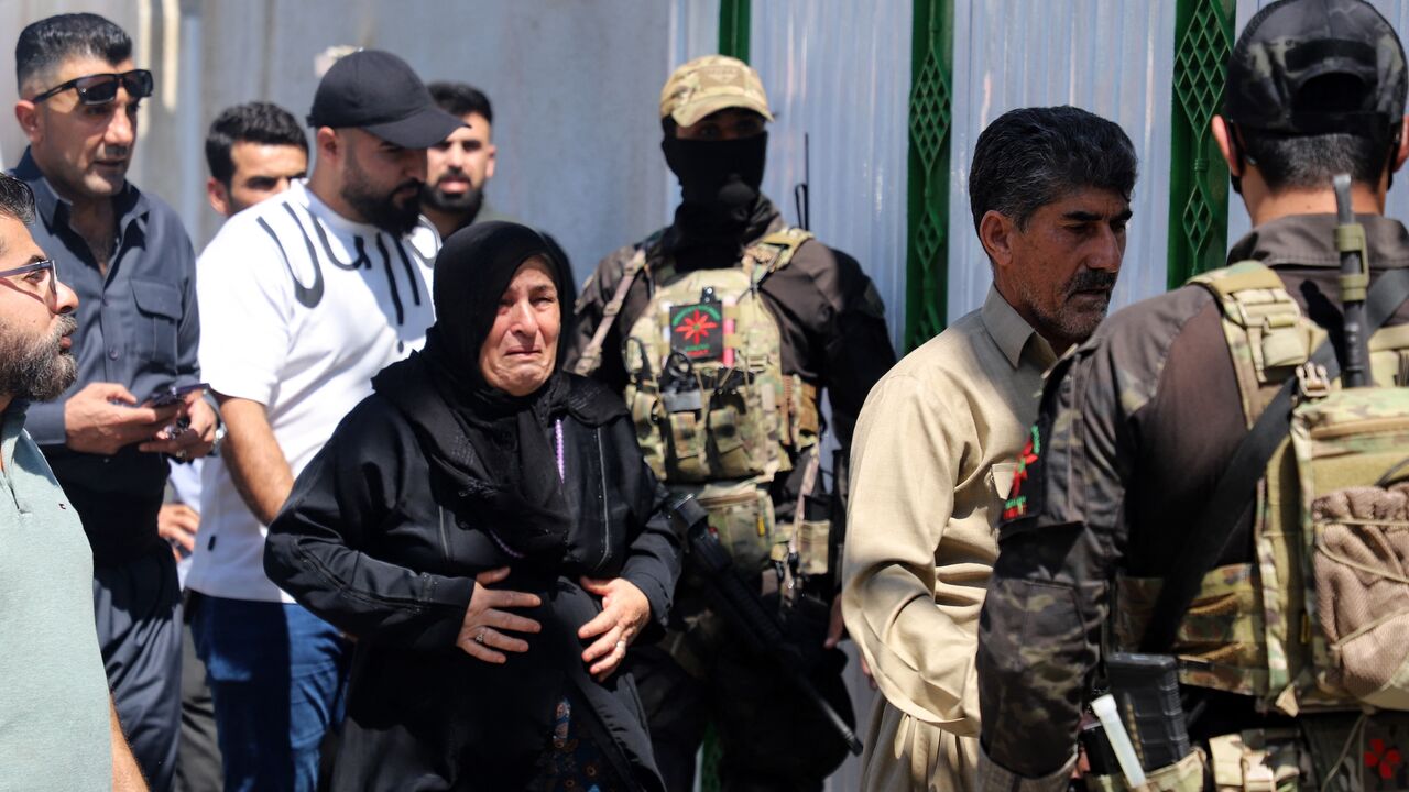 The mother (C) and father (2-R) of one of two women journalists killed in a drone strike walk past Kurdish Asayish security forces.