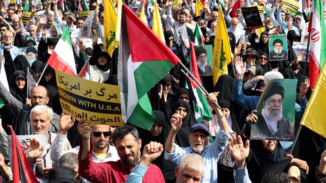 Iranians raise their national flag as well as Palestinian and Lebanon's Hezbollah standards during an anti-Israel protest in Tehran 