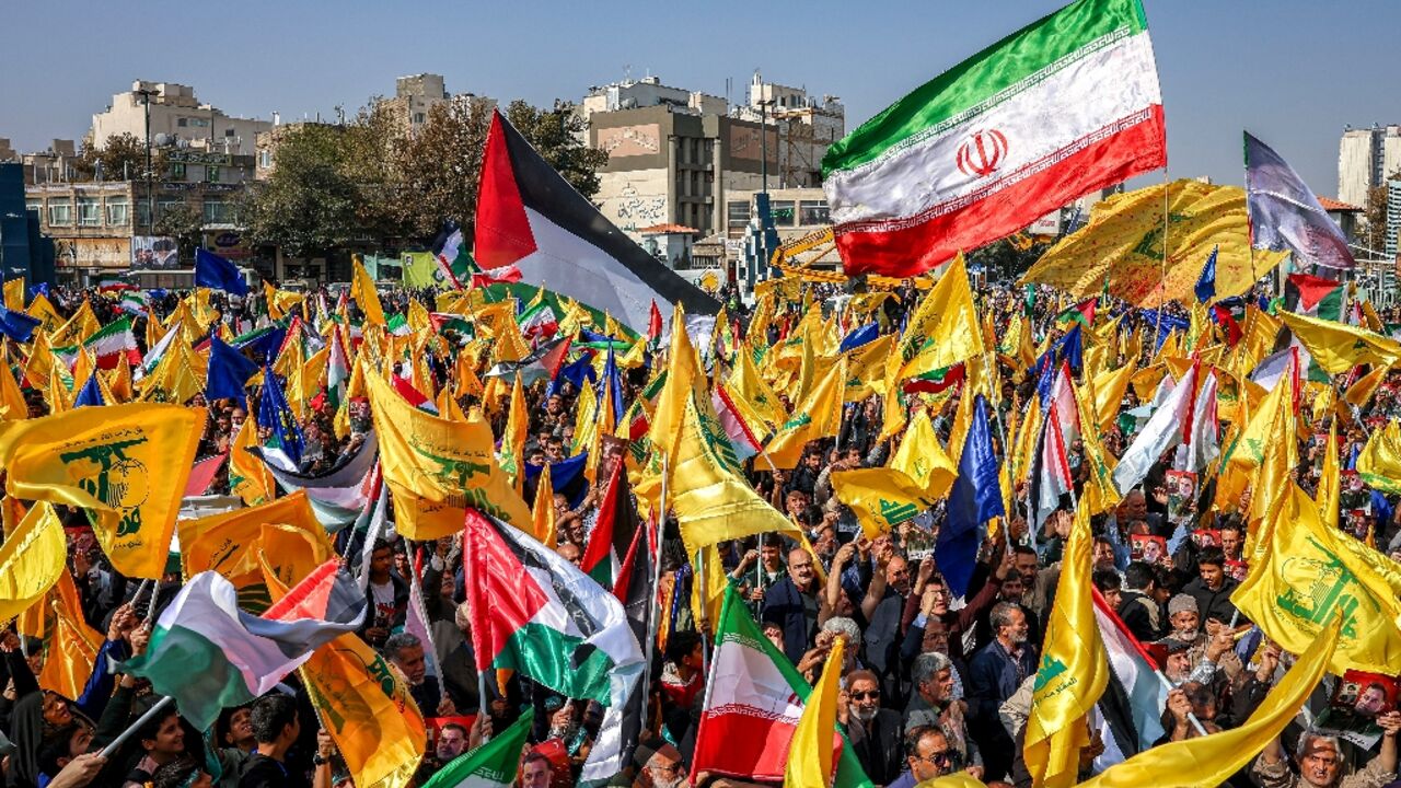 Mourners in Mashhad, Iran, wave flags of Iran, Palestine, and Hezbollah during a funeral procession for General Abbas Nilforoushan, killed in an Israeli air strike in Beirut