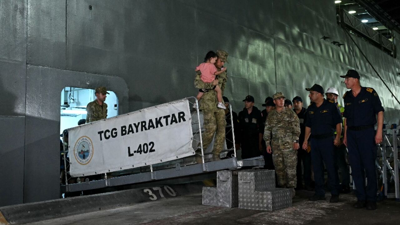 As the first boat docked in Mersin port, Turkish soldiers helped the passengers disembark, one carrying a crying toddler, while another pushed a boy in a wheelchair