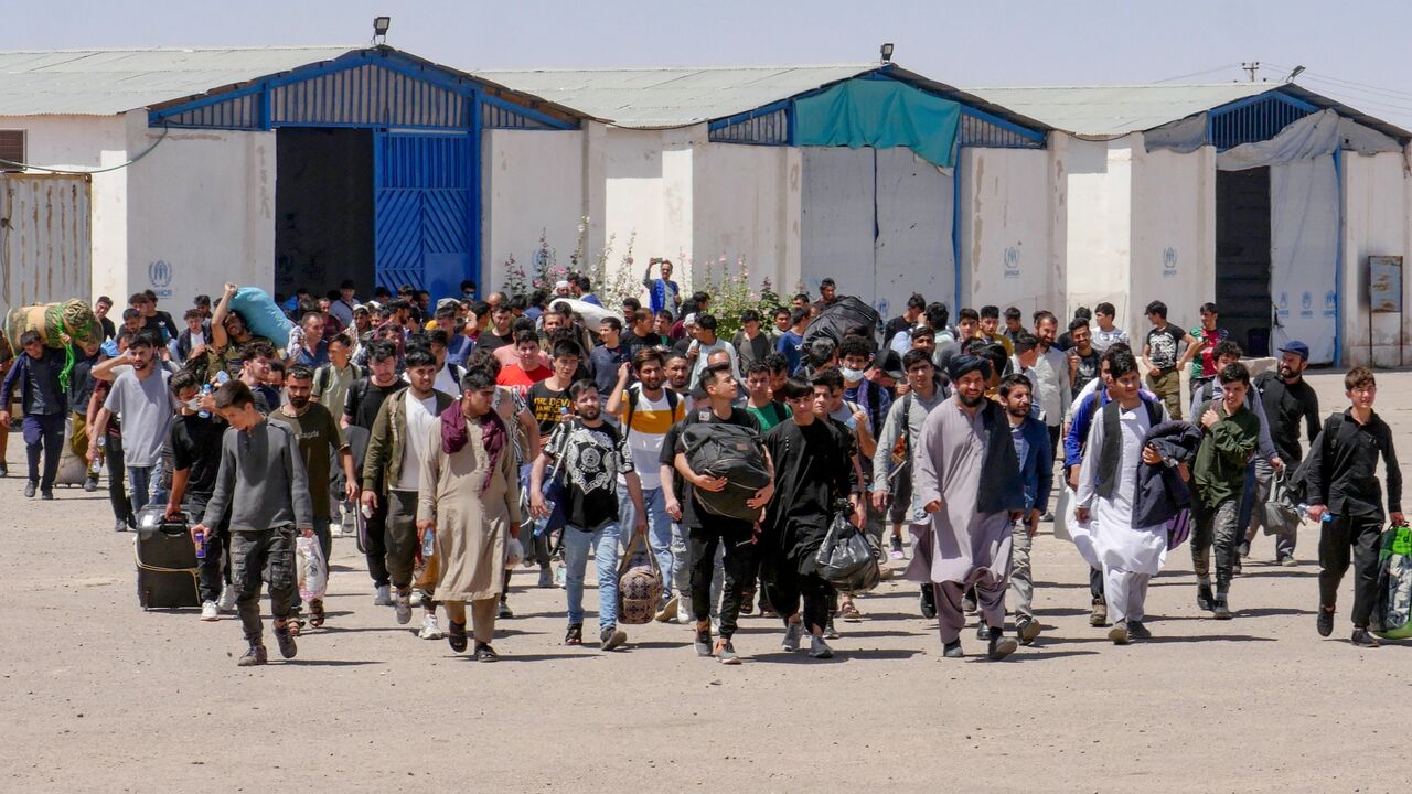 Afghan refugees walk with their belongings after deporting back from Iran at the Islam Qala border between Afghanistan and Iran, in the western Herat province on May 30, 2024. 