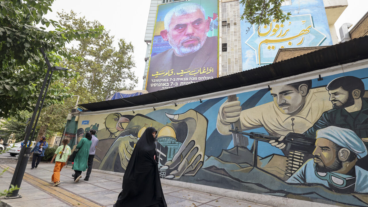 TOPSHOT - People walk past a billboard showing a portrait of newly appointed Hamas leader Yahya Sinwar (top) next to Palestine Square in the Tehran on August 12, 2024. (Photo by ATTA KENARE / AFP) (Photo by ATTA KENARE/AFP via Getty Images)