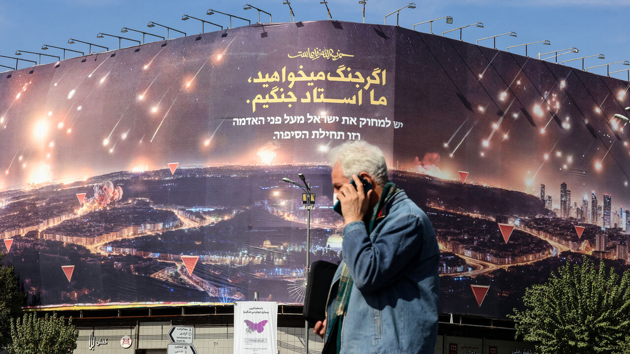 A man walks past an anti-Israel billboard covering the facade of a building in Tehran on October 26, 2024. Residents of Tehran awoke and went about their business as planned on October 26 after their sleep was troubled by Israeli strikes that triggered blasts that echoed across the city. (Photo by ATTA KENARE / AFP) (Photo by ATTA KENARE/AFP via Getty Images)