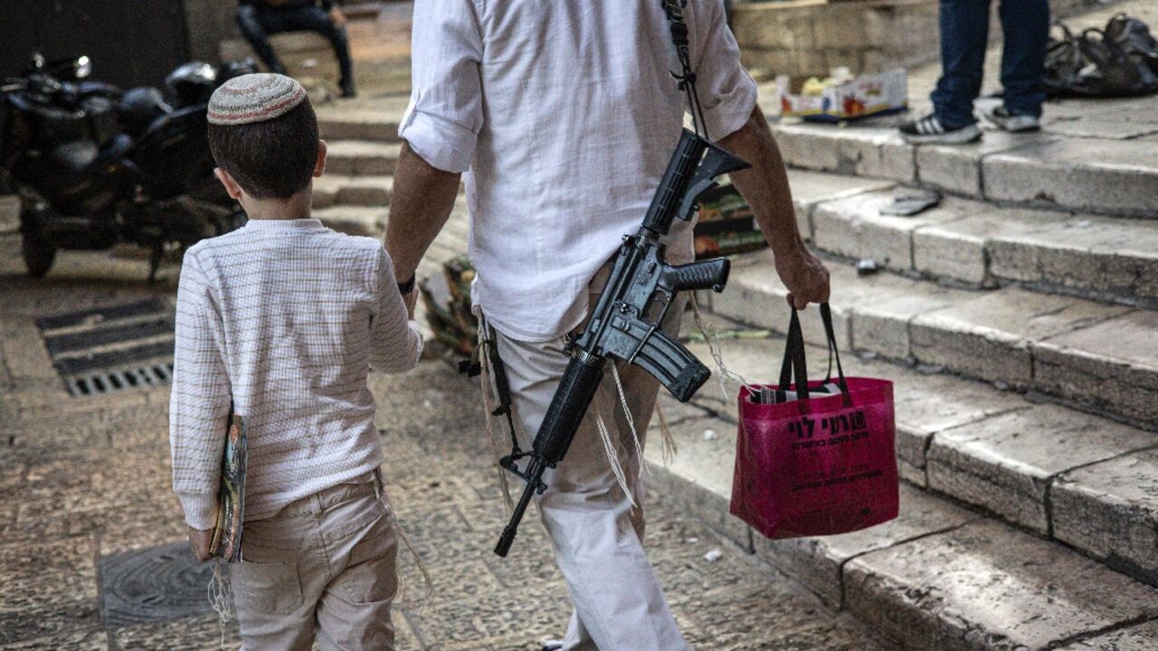 An armed ultra-Orthodox Jewish man holds a child by the hand as he walks in the Old City in Jerusalem at the start of the Jewish holiday of Yom Kippur