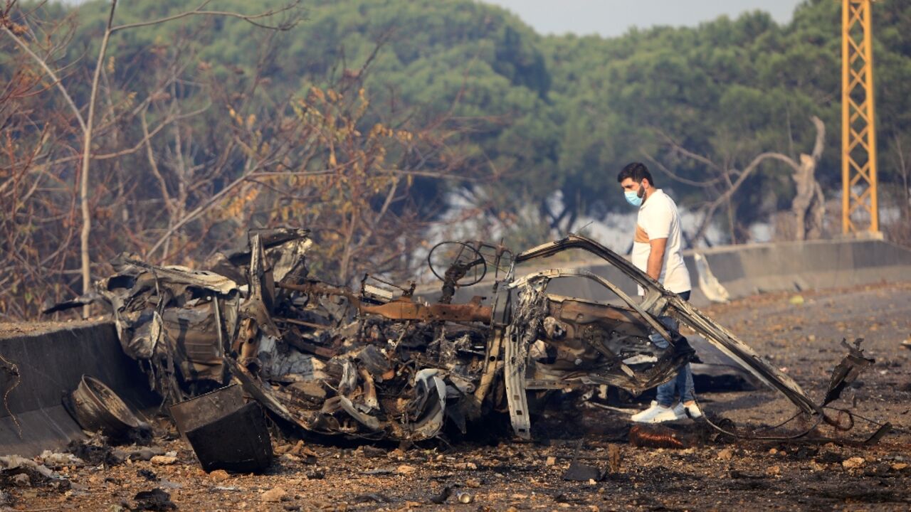 A man checks the wreckage of a vehicle on the Kahhale road after an Israeli strike