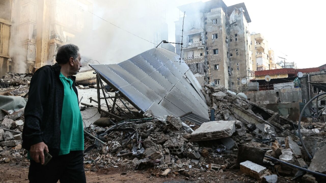 A man walks past the rubble of a building levelled by an Israeli air strike in Beirut's southern suburbs on Saturday