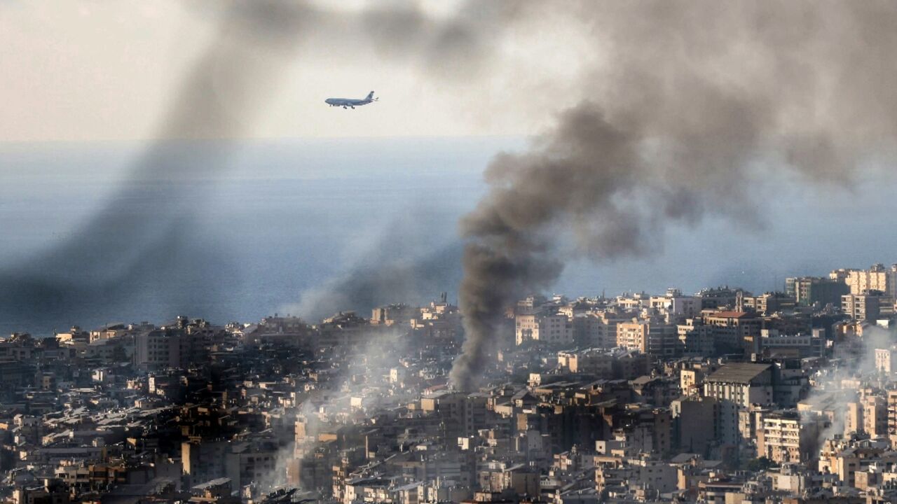 A Middle East Airlines plane approaches Beirut airport, as smoke rises from the site of an Israeli strike that hit the southern suburbs of the Lebanese capital, on November 16, 2024