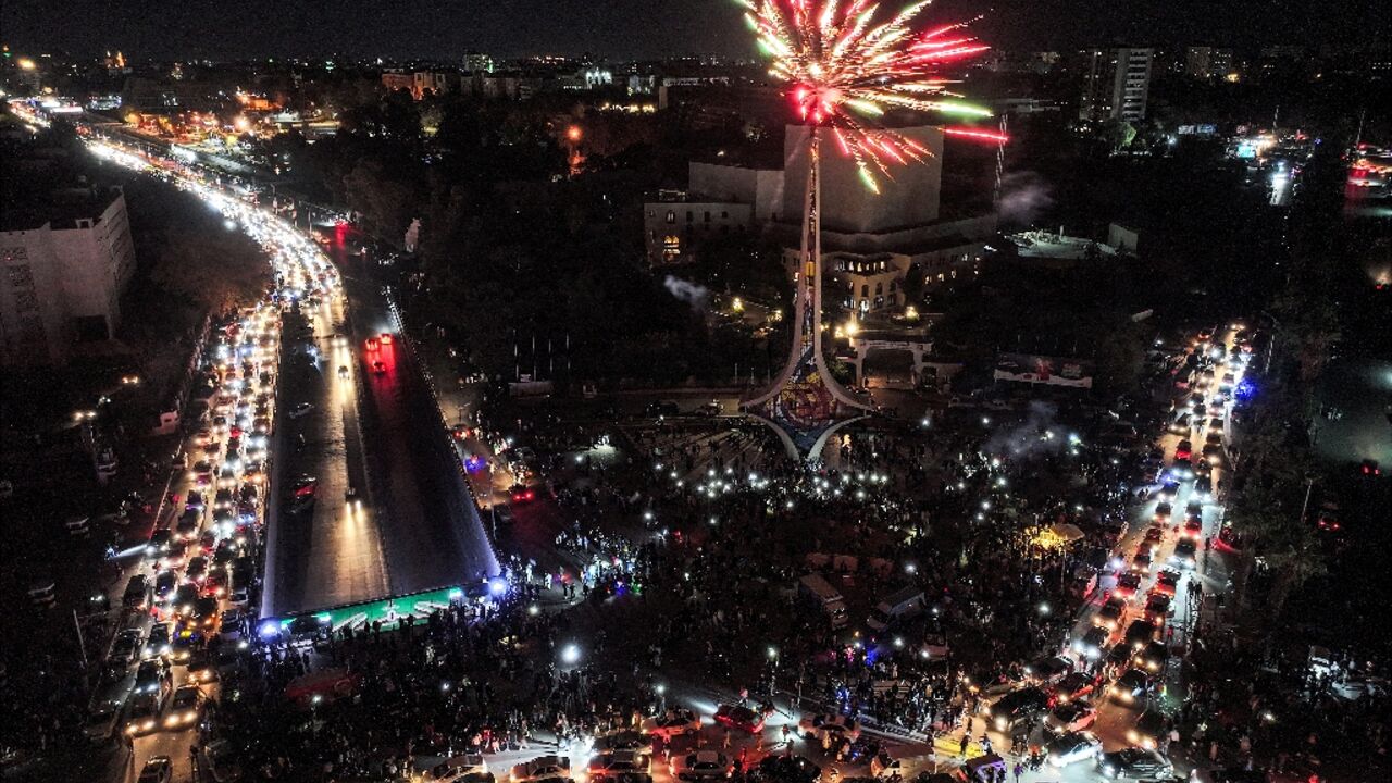 Fireworks erupt above people celebrating the ouster of Syrian president Bashar al-Assad at Umayyad Square in central Damascus