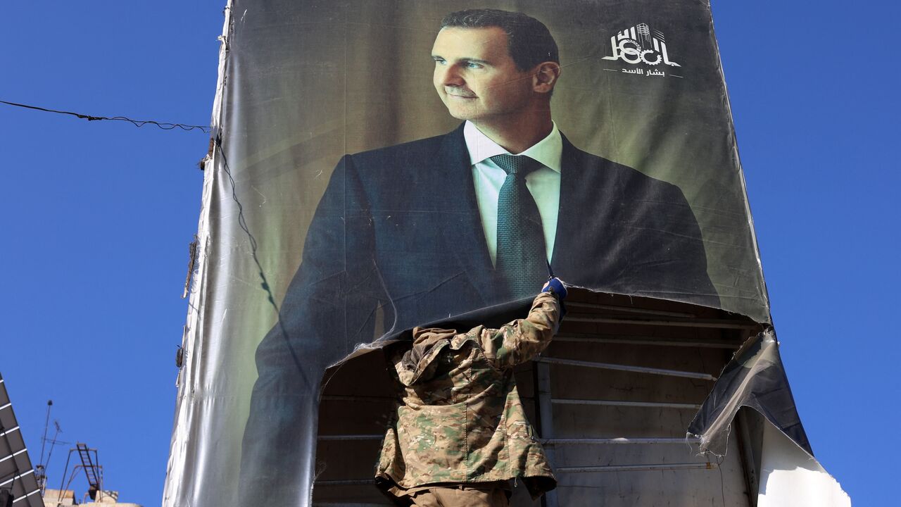 An anti-government fighter tears down a portrait of Syria's President Bashar al-Assad in Aleppo, after jihadis and their allies entered the northern Syrian city, on Nov. 30, 2024. 