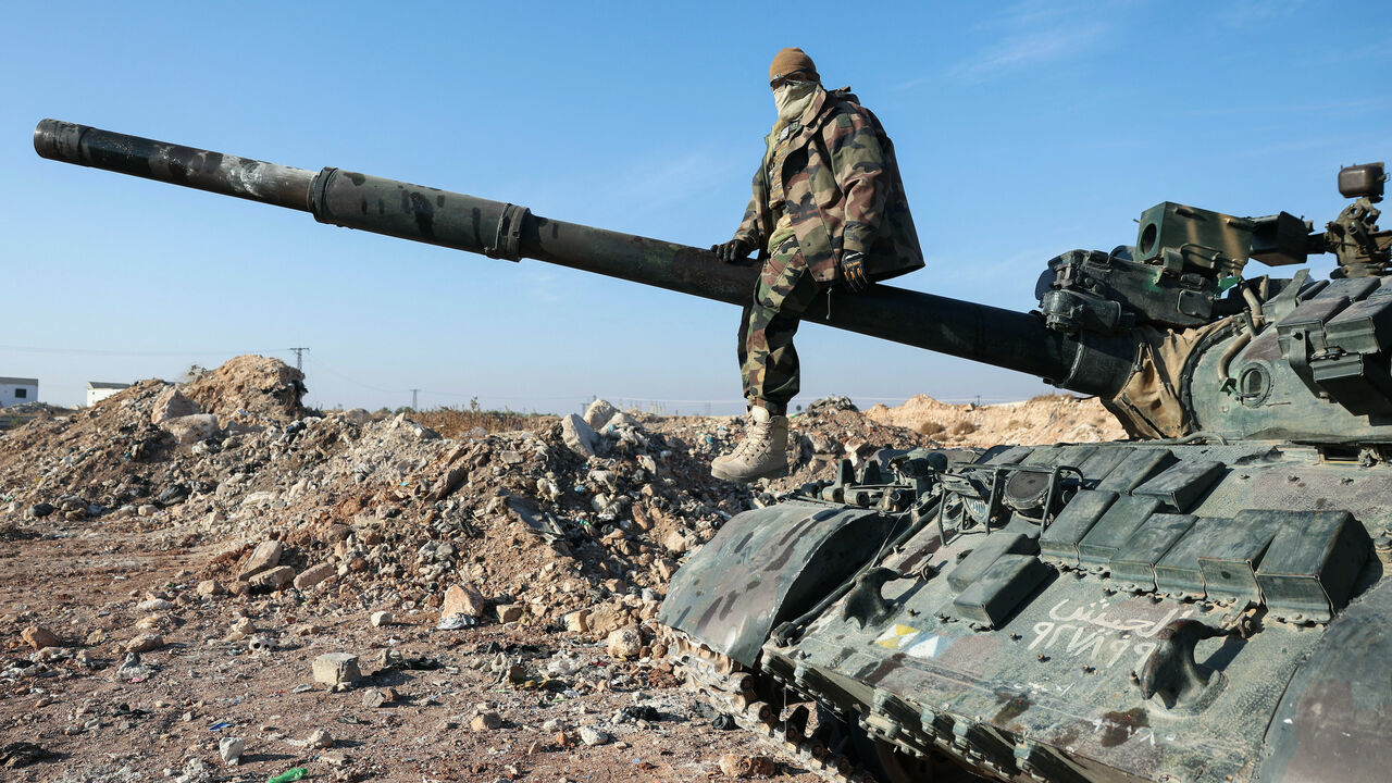 A militant poses for a picture after anti-government fighters seized Syrian army military equipment and vehicles that were abandoned on the highway to Damascus, as they reach the town of Suran north of Syria's Hama city on Dec. 3, 2024. 