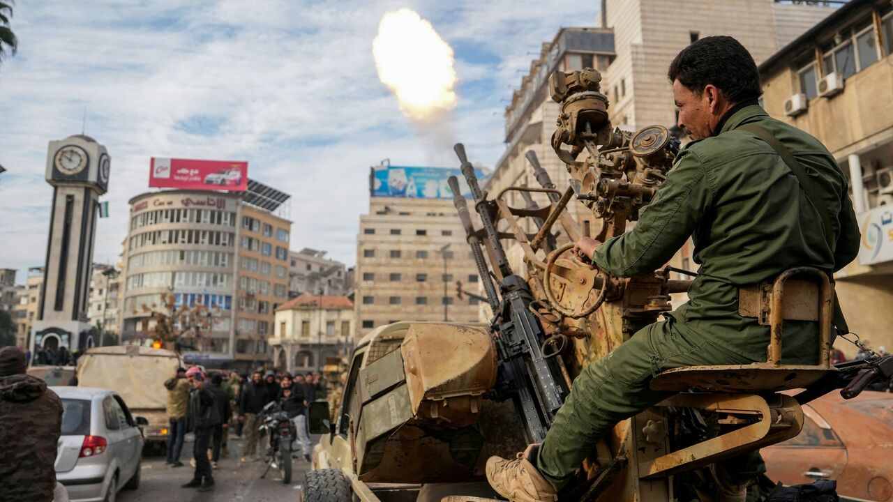 A Syrian rebel fighter fires rounds as people celebrate near the New Clock Tower in the central city of Homs on Dec. 8, 2024. 