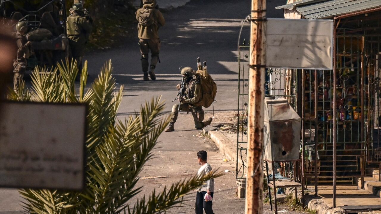 A child looks on as Israeli soldiers patrol in Jubata al-Khashab, in the UN-patrolled Golan Heights buffer zone, which Israeli troops entered after the fall of Syrian president Bashar al-Assad