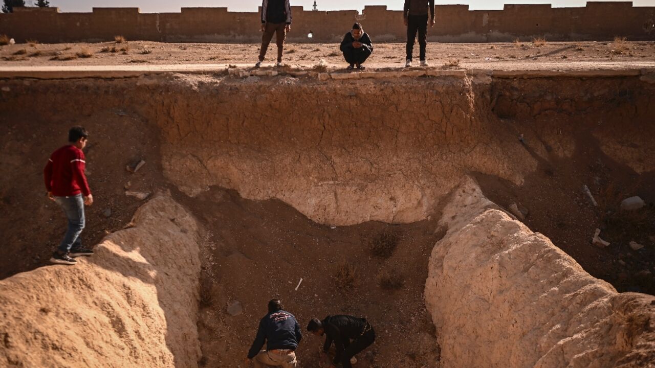 People search for human remains at a trench believed to be used as a mass grave on the outskirts of Damascus