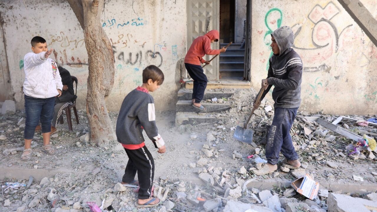 Palestinian children clear debris outside their family home in the Sheikh Radwan neighbourhood in Gaza City