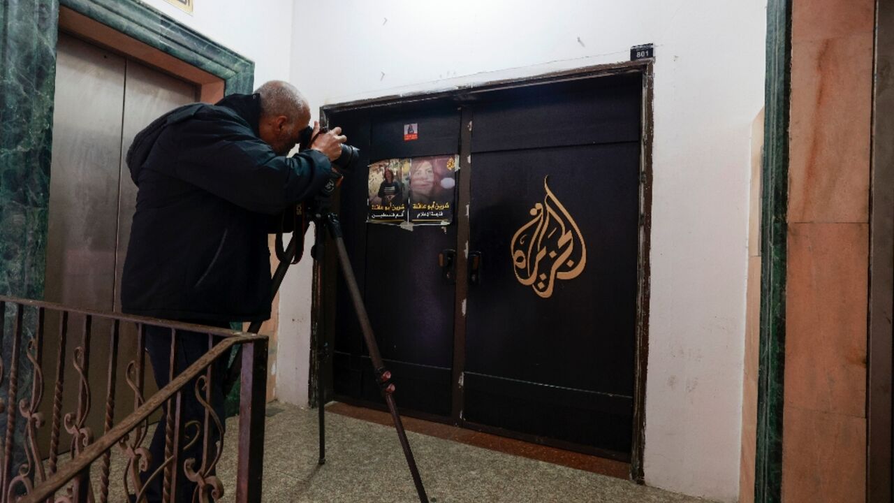 A photographer shoots the closed door of Al Jazeera TV's office in the Israeli-occupied West Bank city of Ramallah following a suspension order from the Palestinian Authority