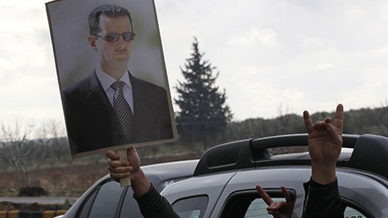 Turkish men flash nationalist gestures while carrying a poster of Syria's President Bashar al-Assad as they drive to the Oncupinar border crossing during a demonstration in support of Syrian government near the Turkish-Syrian border town of Kilis, Gaziantep province, January 12, 2012. REUTERS/Umit Bektas (TURKEY - Tags: POLITICS CIVIL UNREST) - RTR2W6OM