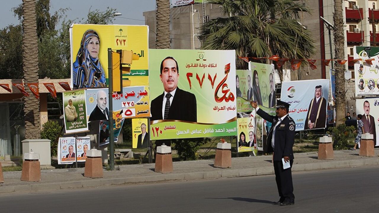 A traffic police officer directs vehicles near election campaign posters in Baghdad April 3, 2014. Iraq's parliamentary election is scheduled for later this month. REUTERS/Ahmed Saad (IRAQ - Tags: POLITICS ELECTIONS) - RTR3JUU9