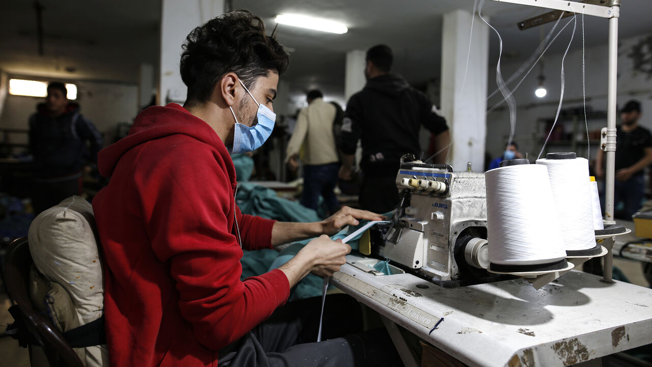 A palestinian worker manufacture protective coverall suits and masks at a workshop in Gaza City on March 31, 2020. amid coronavirus COVID-19 pandemic. Factories in the Gaza Strip used to specialize in the manufacture of shirts and jeans, for despite the closure of many of them in previous years due to the blockade imposed on the Gaza Strip and the inability to export and its aftermath From economic problems that led to the closure of many factories, But with the invasion of the new coronavirus to the world,