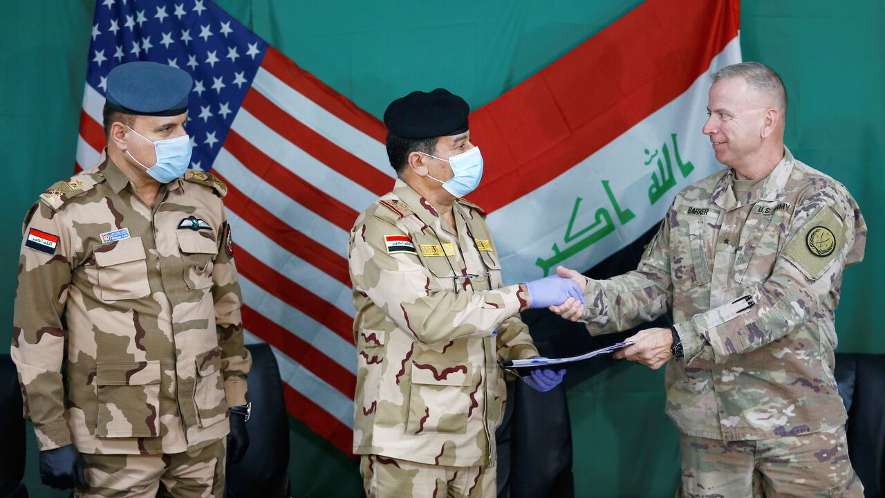 U.S. Brigadier General Vincent Barker shakes hands with Iraqi General Mohammed Fadel, as he wears face mask and gloves, following the outbreak of coronvavirus disease (COVID-19), during the hand over of Qayyarah Airfield West from US-led coalition forces to Iraqi Security Forces, in the south of Mosul, Iraq March 26, 2020. REUTERS/Thaier Al-Sudani - RC2SRF9VPYO2