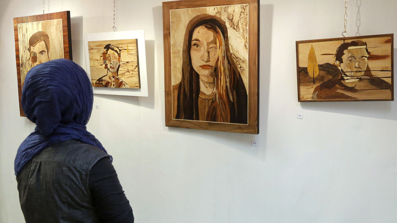 A woman looks at art work made by Iranian victims of acid attacks at the Ashianeh gallery in Tehran on February 28, 2018.
Acid attacks have been an occasional scourge in Iran, with a spate of incidents in 2014 triggering protests and claims they were linked to women wearing "immodest" clothing. Money raised by the show went to Iran's Association of Support of Acid Attack Victims.  / AFP PHOTO / ATTA KENARE        (Photo credit should read ATTA KENARE/AFP via Getty Images)