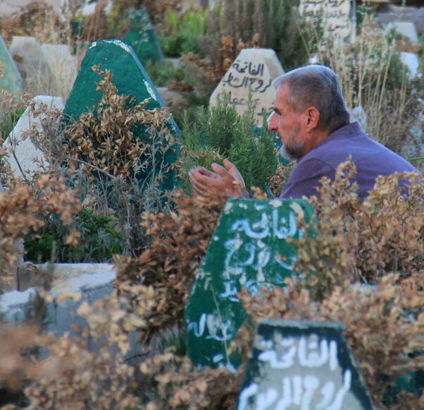 A Syrian man prays on July 12, 2017, at a cemetary in Khan Sheikhun